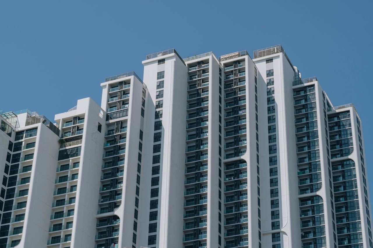 Contemporary high-rise apartment building with unique design and glass facades against a clear blue sky.